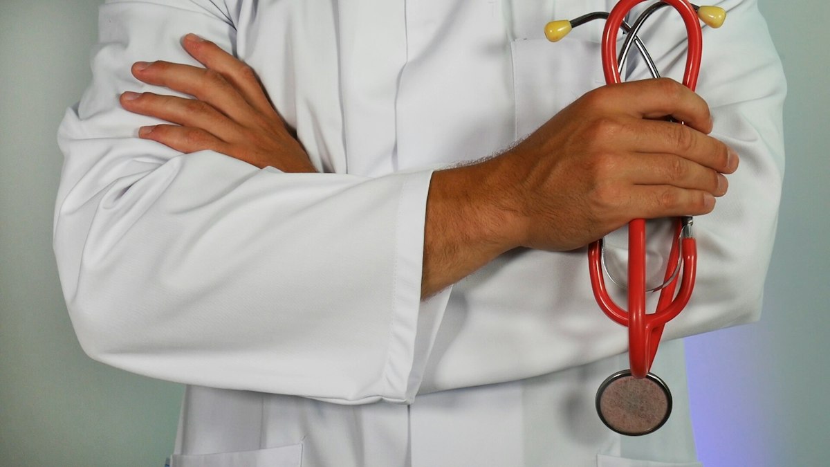 Médico de jaleco segurando um estetoscópio
